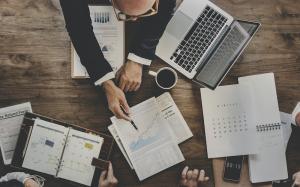 Business workers discussing over graphs on a desk.